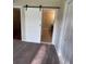 Bedroom entryway showcasing a modern sliding barn door and neutral carpeting throughout at 416 Howard Ave # D, Lakeland, FL 33815