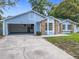 Charming light blue home featuring a well-kept lawn and attached two-car garage at 5452 Higgins Way, Orlando, FL 32808