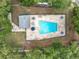 Aerial view of community pool with lounge chairs and umbrellas surrounded by lush green trees and an adjacent covered area at 5452 Higgins Way, Orlando, FL 32808