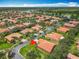 Neighborhood aerial view showcasing homes with red roofs, tree-lined streets, and a picturesque lake in the distance at 572 Sienna Dr, Poinciana, FL 34759