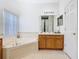 Bright bathroom featuring a large soaking tub and a vanity with a mirror and cabinet storage at 572 Sienna Dr, Poinciana, FL 34759