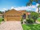 Inviting home featuring a brick driveway, a two-car garage, and manicured landscaping at 572 Sienna Dr, Poinciana, FL 34759
