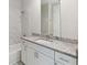 Bathroom vanity with granite countertop, white cabinets, chrome hardware, with tub and tiled shower at 7554 Sunflower Cir, Kissimmee, FL 34747