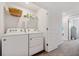 Bright laundry area with appliances, storage shelves, and adjacent hallway creating a practical and efficient space at 955 Grandin St, Davenport, FL 33837