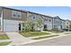 Colorful townhouses with manicured lawns and attached garages sit on a well-maintained street at 955 Grandin St, Davenport, FL 33837