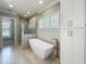 Bathroom featuring a glass shower, soaking tub, shuttered windows, and white storage cabinet at 960 Civitas Way, Winter Garden, FL 34787