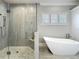 Bright bathroom featuring a glass shower, soaking tub, and shuttered windows at 960 Civitas Way, Winter Garden, FL 34787