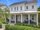 Inviting two-story home with a welcoming front porch, complete with chairs, lush landscaping, and charming curb appeal at 960 Civitas Way, Winter Garden, FL 34787
