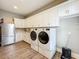 Well-lit laundry room featuring front loading washer and dryer with white cabinets and luxury vinyl plank flooring at 960 Civitas Way, Winter Garden, FL 34787