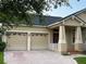 Charming home with a well-manicured lawn, mature trees, and a brick paver driveway leading to a 2-car garage at 9721 Old Patina Way, Orlando, FL 32832