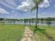 Backyard leads to the lake, showcasing a lush lawn, stone path, and palm tree at 9824 Secret Cove Ln, Orlando, FL 32832
