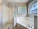 This bathroom features a shower with glass door, a bathtub, and a view of the backyard at 9824 Secret Cove Ln, Orlando, FL 32832
