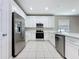 Kitchen with stainless steel appliances, white cabinets and countertops, plus tile floor at 9824 Secret Cove Ln, Orlando, FL 32832