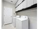 Well-organized laundry room with white appliances and built-in storage cabinets above washer and dryer at 9824 Secret Cove Ln, Orlando, FL 32832