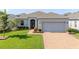 Charming single-story home featuring a brick driveway, well-manicured lawn, and a two-car garage at 1021 Golden Dawn Loop, Minneola, FL 34715