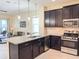 Modern kitchen with granite countertops, stainless steel appliances, dark wood cabinets, and seamless integration to the living area at 1021 Golden Dawn Loop, Minneola, FL 34715