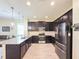 Modern kitchen featuring dark cabinets, granite countertops, stainless steel appliances, and a spacious island at 1021 Golden Dawn Loop, Minneola, FL 34715