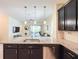 Open-concept kitchen features granite counters, dark wood cabinets, and stainless steel appliances overlooking the living room at 1021 Golden Dawn Loop, Minneola, FL 34715
