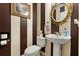 Stylish powder room with striped walls, ornate mirror, pedestal sink, and classic fixtures at 114 Harwood Cir, Kissimmee, FL 34744