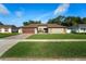 Well-maintained single-story home with a brick driveway, two-car garage, and manicured lawn at 12542 Idaho Woods Ln, Orlando, FL 32824