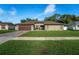 Well-maintained single-story home with a brick driveway, lush grass and mature landscaping at 12542 Idaho Woods Ln, Orlando, FL 32824