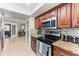 Galley kitchen with wooden cabinets, granite countertops, stainless steel appliances, and view to the home's interior at 12542 Idaho Woods Ln, Orlando, FL 32824