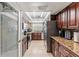 Galley kitchen featuring stainless steel appliances, granite countertops, and wood cabinets offering ample storage at 12542 Idaho Woods Ln, Orlando, FL 32824
