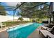 Refreshing screened-in pool with lounge chairs, palm trees, and ample deck space at 12542 Idaho Woods Ln, Orlando, FL 32824
