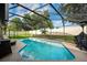 Screened-in pool area with ample seating, barbecue grill, and lush landscaping at 12542 Idaho Woods Ln, Orlando, FL 32824