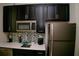 Modern kitchen with stainless steel appliances, mosaic backsplash, and black cabinets, perfect for culinary creations at 153 Taft Dr, Davenport, FL 33837