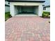 View of the garage with a brick driveway leading up to it and lawn on either side at 2505 Merseyside Ct, Haines City, FL 33844