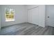 Well-lit bedroom with gray vinyl floors and a large window, accompanied by a closet for storage at 2580 Gallardia Dr, Lake Wales, FL 33898