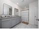 Modern bathroom with double vanity, granite countertop, large mirrors, and a shower with stylish striped curtain at 2726 Harmonia Hammock Rd, Harmony, FL 34773