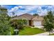 Exterior shot of home with manicured lawn, two-car garage and verdant plantings at 2726 Harmonia Hammock Rd, Harmony, FL 34773