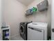 A compact laundry room with a washer, dryer, and storage shelves at 2726 Harmonia Hammock Rd, Harmony, FL 34773