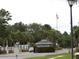 View of the gated entrance with a security guard, American flag, palm trees, and lush landscaping at 3074 Bay Laurel N Cir, Kissimmee, FL 34744