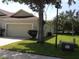 View of a single-story home featuring a two-car garage, green lawn, and mature trees at 3074 Bay Laurel N Cir, Kissimmee, FL 34744