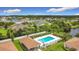 Aerial view of the pool area, showcasing a pool, fence, mature trees, surrounding landscape and nearby residential buildings at 3428 Village Green Ct, St Cloud, FL 34772