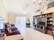 Open living room with tile floors, dark wood entertainment center, and comfortable brown leather sofa at 3428 Village Green Ct, St Cloud, FL 34772
