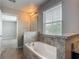 Bathroom with a tub, a mirror, a light fixture, and a tiled countertop next to a window at 3603 Sanctuary Dr, St Cloud, FL 34769