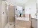 Bathroom featuring a tiled shower with glass door, soaking tub, and decorative details at 4109 Vessel Ct, Kissimmee, FL 34746
