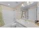 A bathroom with a shower-tub combo, white tile, a toilet, a vanity with sink and a large mirror at 423 Paloma Dr, Davenport, FL 33837