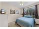 Bedroom with blue bedding, neutral walls, a side table with a lamp, and a window with patterned curtains at 423 Paloma Dr, Davenport, FL 33837