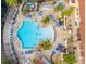 Aerial view featuring a sparkling blue community pool with lounge chairs and tables, surrounded by lush landscaping at 4697 Golden Beach Ct, Kissimmee, FL 34746
