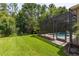 Lush green backyard features a screened-in pool enclosure, providing a relaxing outdoor space surrounded by trees at 4697 Golden Beach Ct, Kissimmee, FL 34746