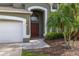 Close-up of the front entrance, highlighting the arched doorway, garage, and charming landscaping at 4697 Golden Beach Ct, Kissimmee, FL 34746