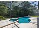A screened-in swimming pool with a connected spa and a spacious concrete deck for outdoor relaxation and leisure at 4697 Golden Beach Ct, Kissimmee, FL 34746