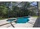 A screened-in swimming pool with a connected spa and a spacious concrete deck for outdoor relaxation and leisure at 4697 Golden Beach Ct, Kissimmee, FL 34746