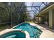 A screened-in pool area featuring a luxurious in-ground pool and spa with outdoor seating and lush greenery nearby at 4697 Golden Beach Ct, Kissimmee, FL 34746