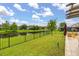 Expansive backyard with lush green grass, black metal fence, and a tranquil lake view at 4952 Creekside Park Ave, Orlando, FL 32811
